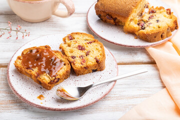 Homemade cake with raisins, almonds, soft caramel and a cup of coffee on a white wooden background. Side view, close up.