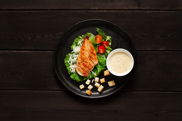 Caesar salad with chiken , on a black  wooden table, top view, no people,