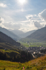 Naklejka premium View into a deep mountain valley with houses and roads directly against the sun - France