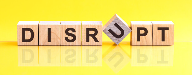 disrupt word is made of wooden building blocks lying on the yellow table, concept - obrazy, fototapety, plakaty