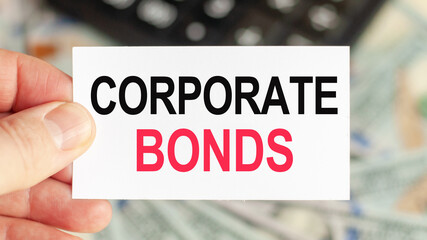 A man holds a piece of paper with the text: corporate bonds. Business and finance concept.