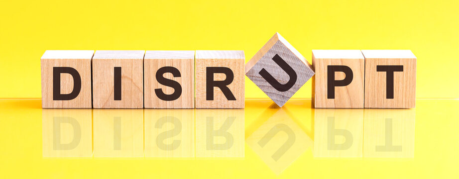 Disrupt Word Is Made Of Wooden Building Blocks Lying On The Yellow Table, Concept