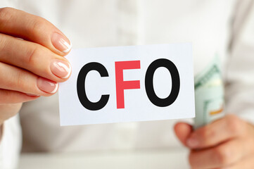 On the table are bills, a bundle of dollars and a sign on which it is written - CFO. Finance and economics concept.