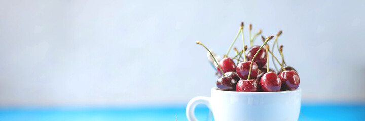 Cherry banner background. Red summer cherry berries in a cup on a background. Summer fruits and Healthy food concept. tasty cherries.Panoramic banner with Copy space.