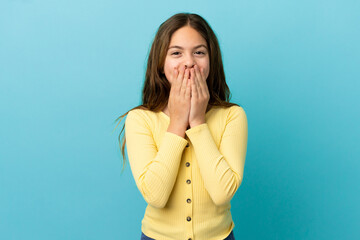 Little caucasian girl isolated on blue background happy and smiling covering mouth with hands