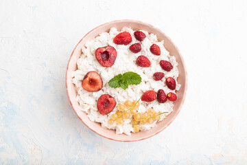 Rice flakes porridge with milk and strawberry in ceramic bowl on white concrete background. Top view.