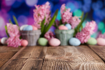 Easter background.  Easter eggs and spring flowers. Rustic wooden table. Pastel colors bokeh. Place for typography.