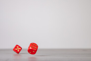 the die is cast, red dice falling on a gray wooden board