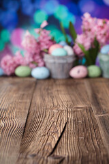 Easter background.  Easter eggs and spring flowers. Rustic wooden table. Pastel colors bokeh. Place for typography.