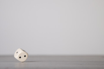 the die is cast, one white dice on a gray wooden board