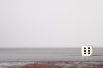 the die is cast, one white dice on a gray wooden board