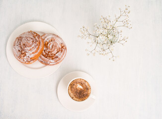 Cinnabon buns. Cinnamon rolls with spices and apple filling and cup of cappuccino on white background. Swedish or American breakfast.