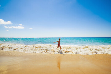 kid on vacations at seaside running in the water