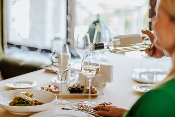 Serving of white wine to the customer in the restaurant.