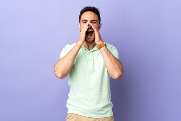 Young handsome man isolated on purple background shouting and announcing something