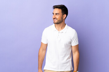Young handsome man isolated on purple background looking to the side and smiling