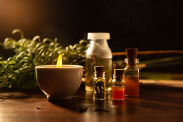 Aromaterapia e fitoterapia. Terapia holística. Vidros com óleos essenciais, vela acesa e ervas ao fundo.