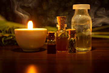 Obraz na płótnie Canvas Aromaterapia e fitoterapia. Terapia holística. Vidros com óleos essenciais, vela acesa e ervas ao fundo.