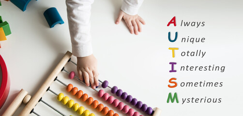 children's hands play with a bright toy on a white table. The word autism is written. autism...