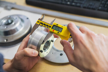worker measures a metal part with a vernier caliper