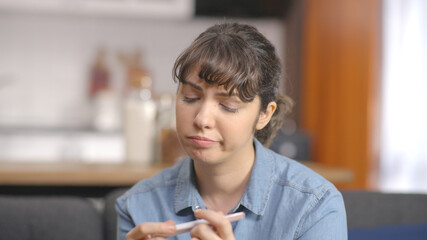 Young woman is eagerly awaiting pregnancy test result. Unhappy and sad young woman with negative...