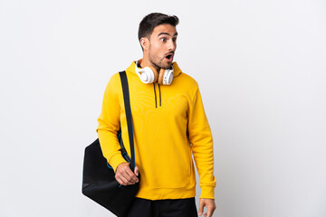 Fototapeta premium Young sport man with sport bag isolated on white background doing surprise gesture while looking to the side
