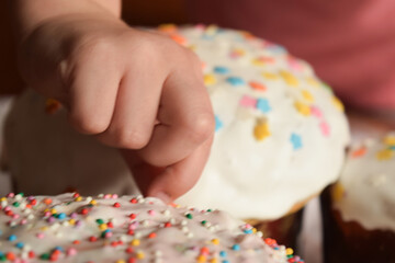 Festive Easter cakes with white icing and sprinkling, festive composition. The hand of a child, The image of family and home comfort.