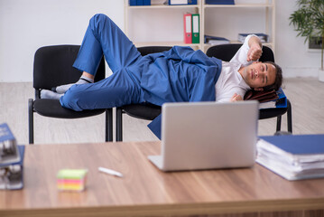 Young male employee sleeping in the office on chairs