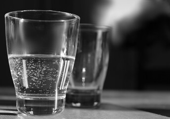glass of cool clear water sitting on table in black and white stock photo