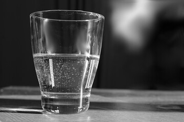 glass of cool clear water sitting on table in black and white stock photo