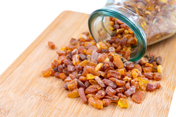 Small raw ambers scattered on a wooden board. The material used for the production of ornaments and...