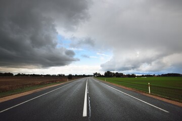Empty highway (asphalt road) through the fields. Dramatic sky before the rain and thunderstorm....