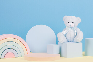Baby kid toy background. Blue teddy bear, colorful wooden rainbow and geometric shapes podium...