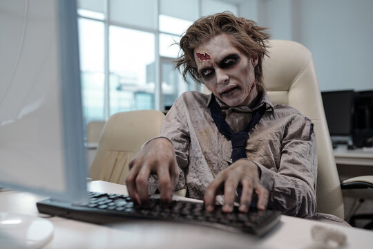 Spooky businessman with zombie body painting looking at computer screen and typing