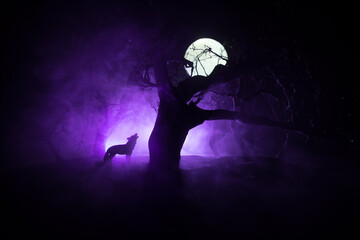 Silhouette of howling wolf against dead forest skyline and full moon. Creative artwork decoration.