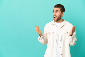 Handsome blonde man over isolated blue background with surprise facial expression