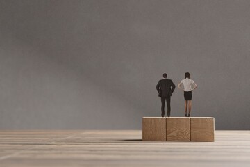 Miniature man and woman standing on the wooden blocks. The concept of equal opportunities for...