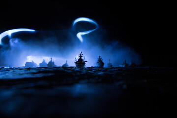 Silhouettes of a crowd standing at blurred military war ship on foggy background. Selective focus....