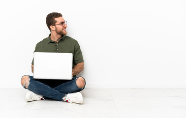 Young man sitting on the floor looking to the side and smiling