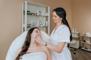 Esthetician or facialist making facial cleansing procedure