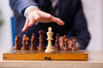 Young male employee playing chess at workplace