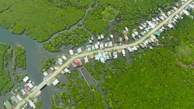 Rural road in the Philippines in the mangroves and the village with houses top view. Siargao island, Philippines.