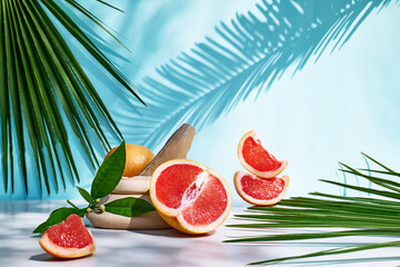 Fresh healthy grapefruit on sunlight with hard shadows. Minimal food creative concept on blue pastel background. Grapefruit slices citrus fruits.