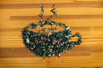 Arrangement of floral green tea laid out in the form of a mug on a wooden background. View from...