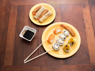 Top view of sushi in yellow plates on a wooden table. Maki. Sashimi. Salmon, Asian, Japanese.