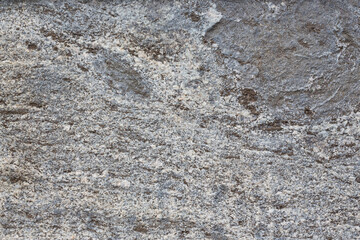Granite texture. Natural gray granite with a grainy pattern. Stone background. Solid rough surface of rock. Durable construction and decoration material. Close-up.