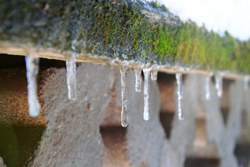 Ice icicles dangling from the wall. Winter time, frozen water