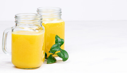 Orange juice and green leaves on a white background.A glass of orange juice Healthy food. Vegan food