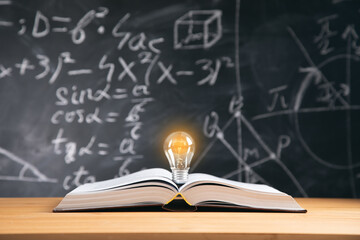 light bulb on book with blackboard background