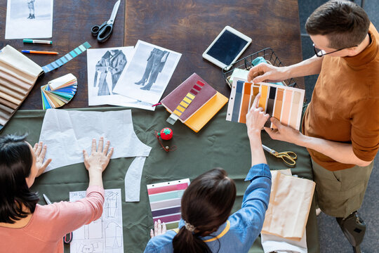 Group of young fashion designers discussing textile samples for new seasonal collection